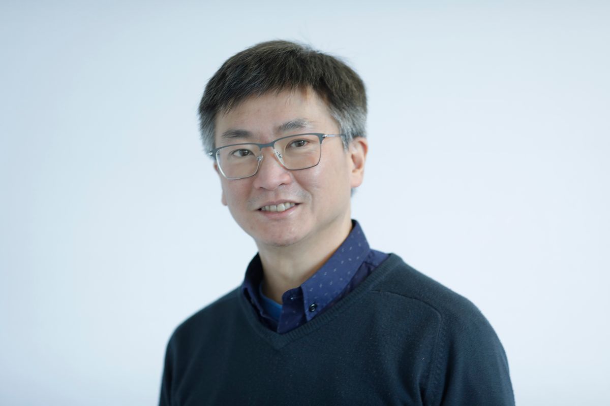 A Headshot Of Terence Leung Wearing A Blue Shirt And Sweater.