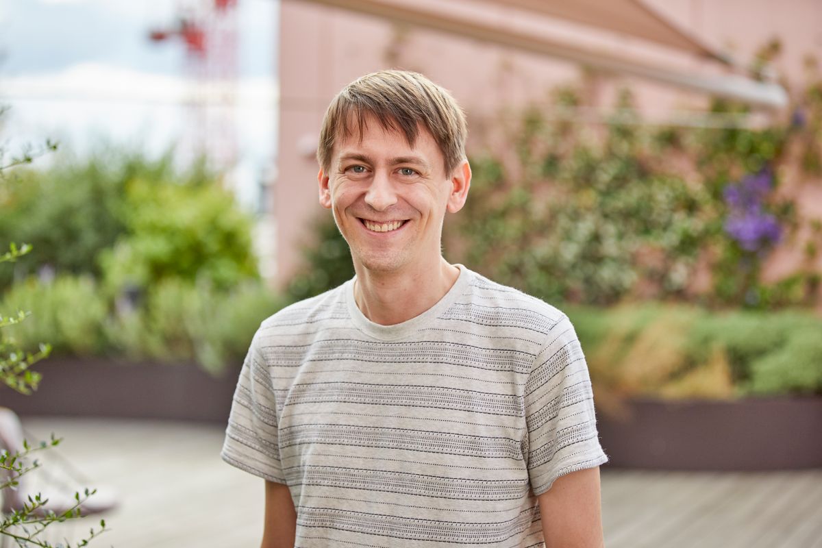 A photo of John Jumper outdoors wearing a gray striped T-shirt.