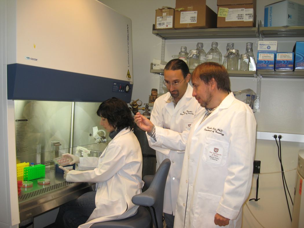 Claudio Soto, Rodrigo Morales, and Claudia Duran-Aniotz wear white coats while analyzing data in a lab. Claudio Soto, Rodrigo Morales, and Claudia Duran-Aniotz wear white coats while analyzing data in a lab.