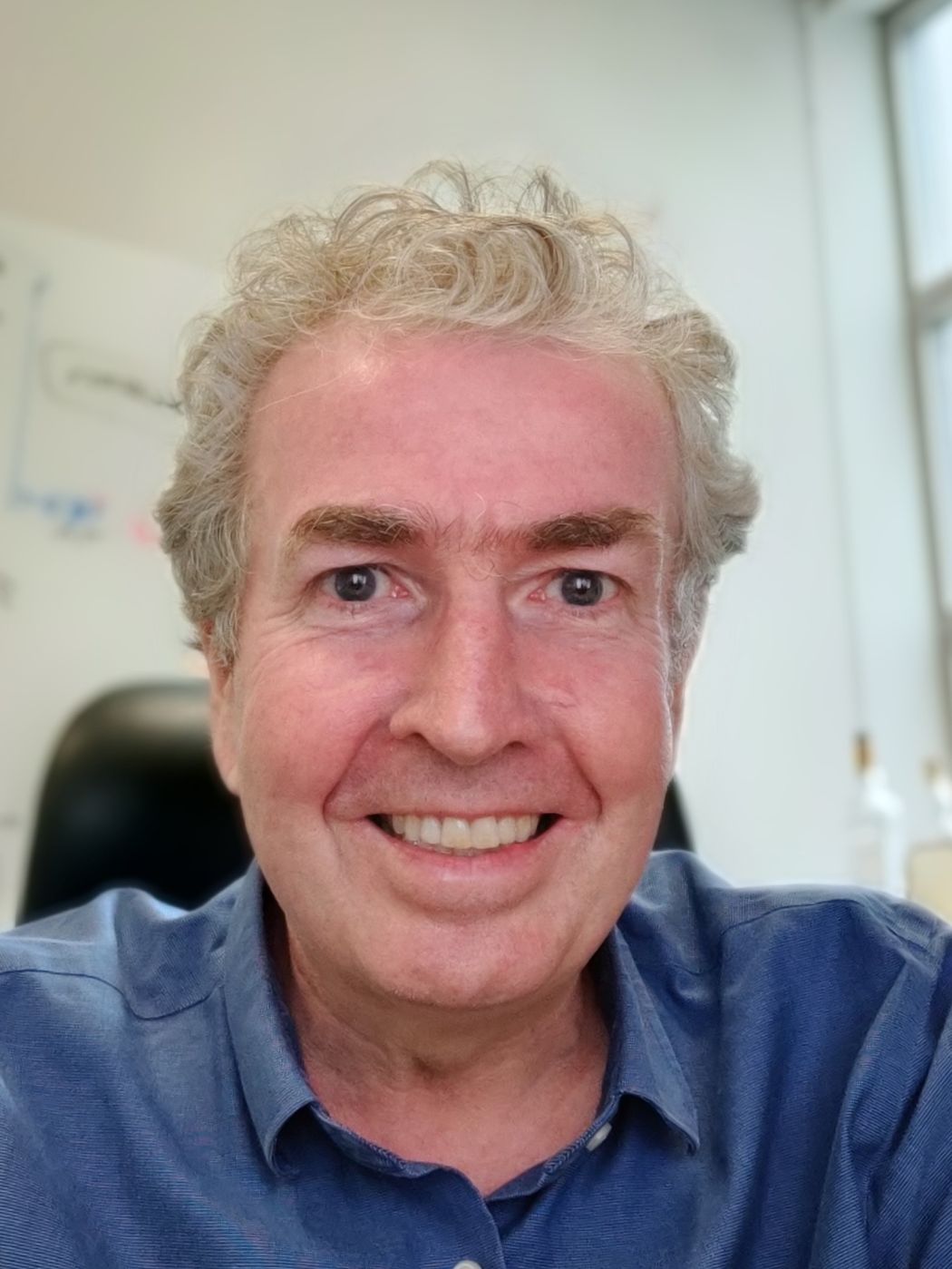 Tim Ryan smiles in a blue shirt against a white wall