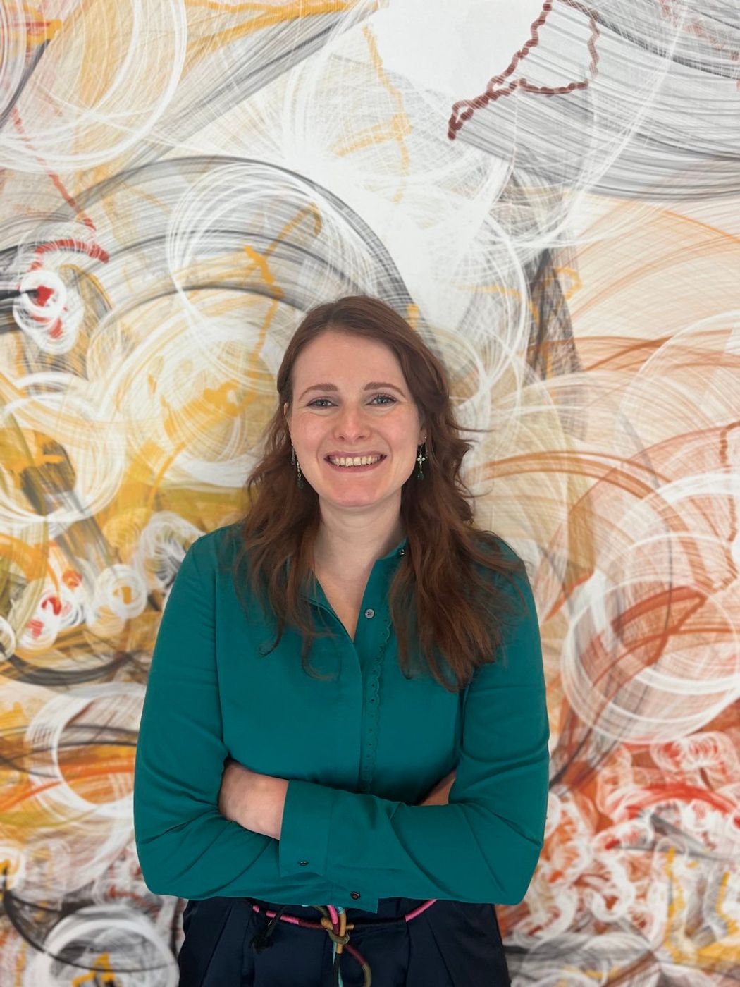 Julia Fröse stands in front of an abstract mural and wears a green shirt. Julia Fröse stands in front of an abstract mural and wears a green shirt.