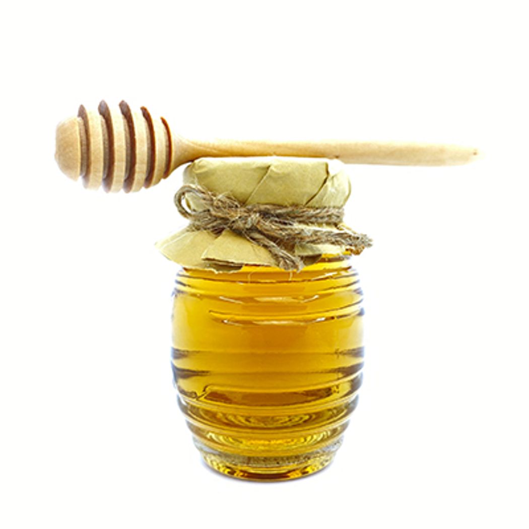 A vintage honey bee bottle glass with a wood dipper. A vintage honey bee bottle glass with a wood dipper.