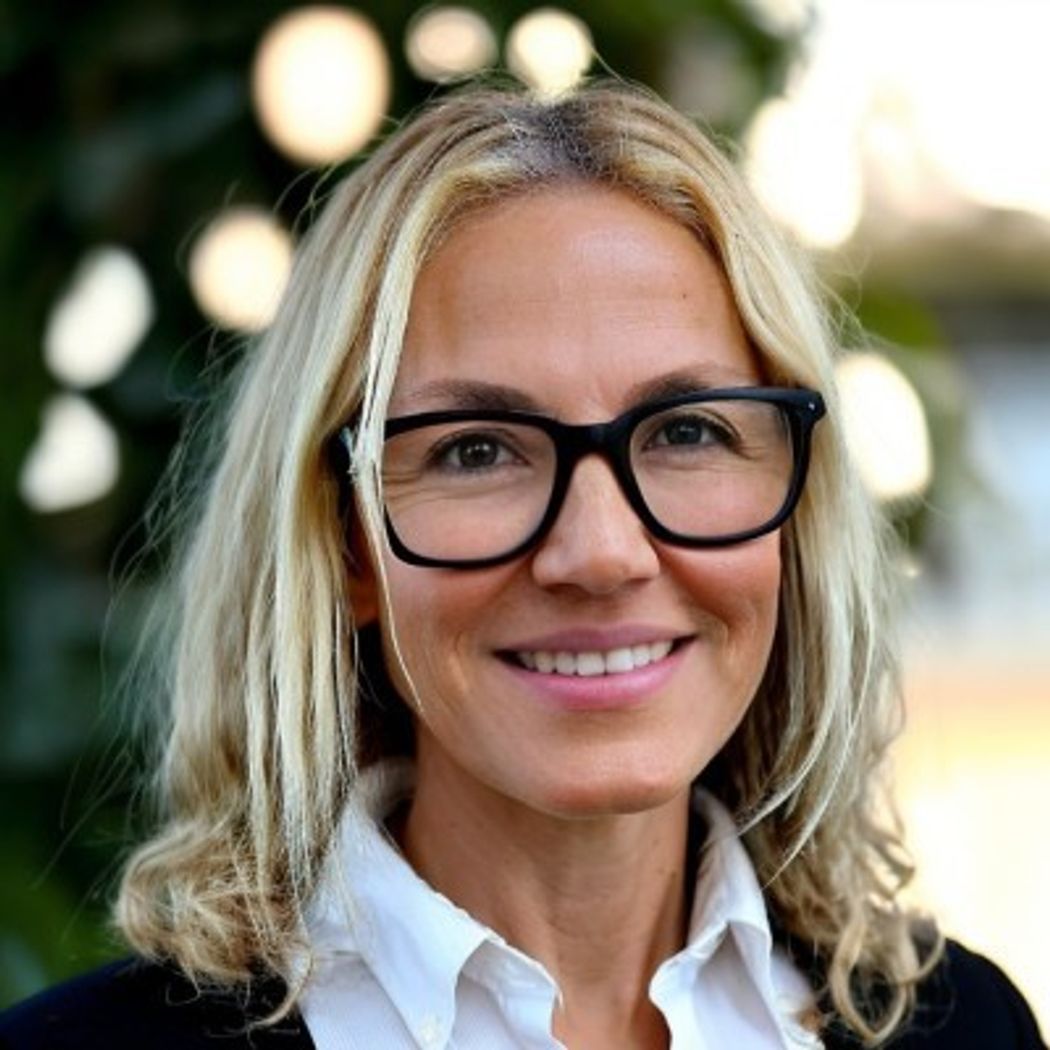 A headshot of Elena Koundourakis wearing large black frames, white shirts, and black sweaters. A headshot of Elena Koundourakis wearing large black frames, white shirts, and black sweaters.