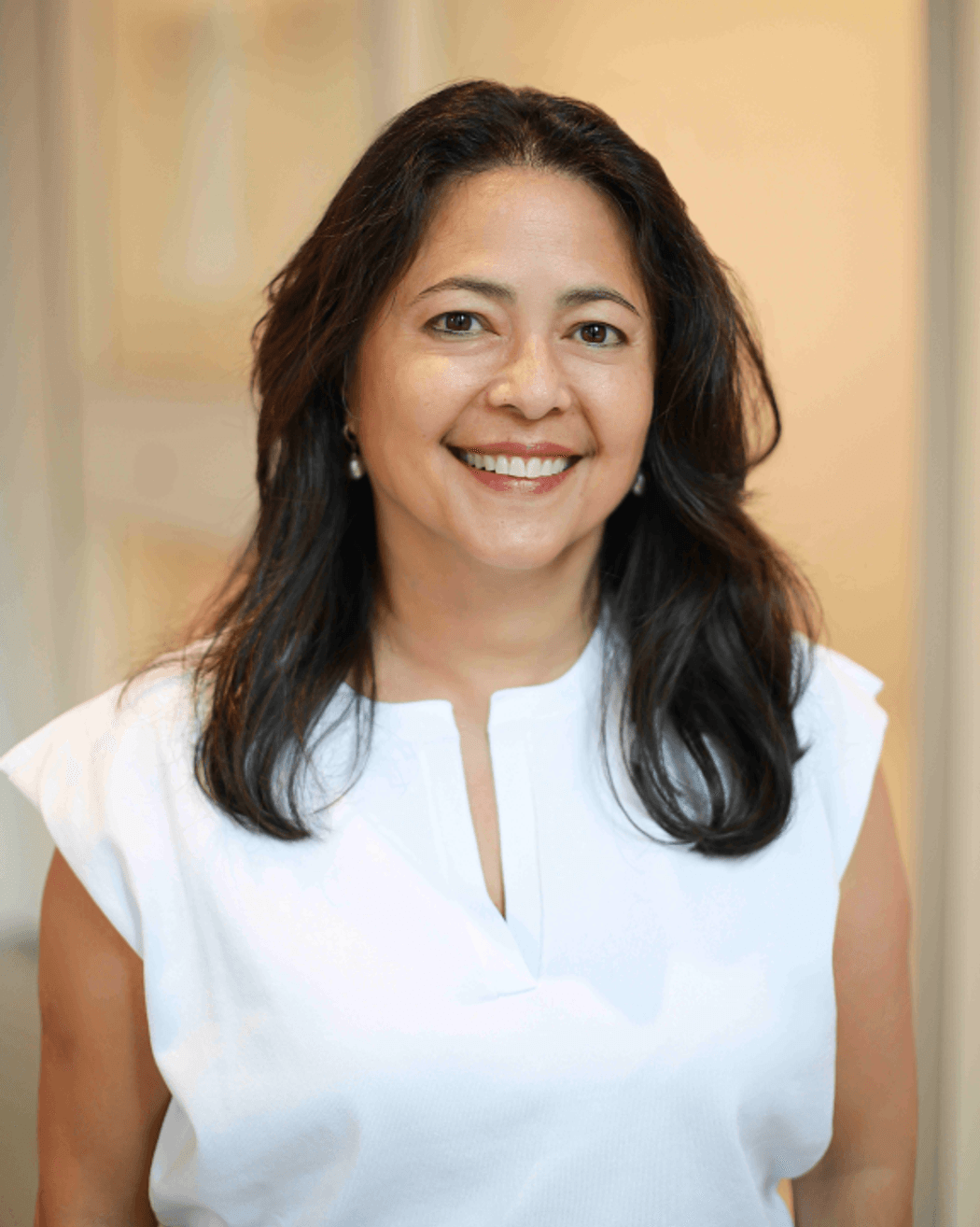 Sandi See Tai wears a striped shirt and smiles in a gray and white photo.