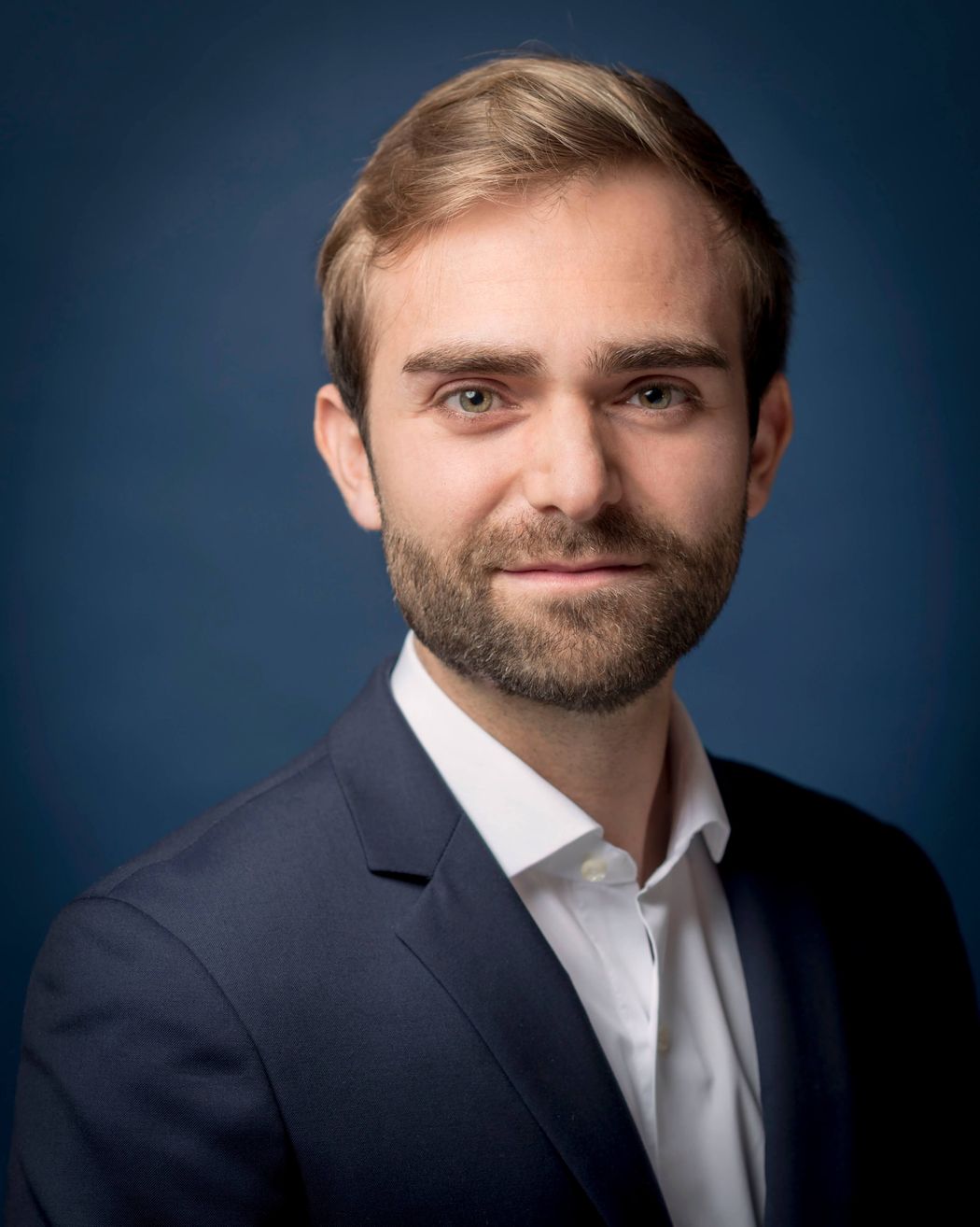 Xavier Duportet wears a dark blue suit jacket in front of a blue background.