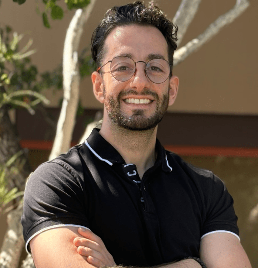 Marco Corbo wears a black polo shirt and glasses and smiles. Marco Corbo wears a black polo shirt and glasses and smiles.