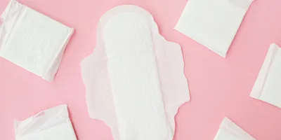 White menstrual pads are shown on a pink background.