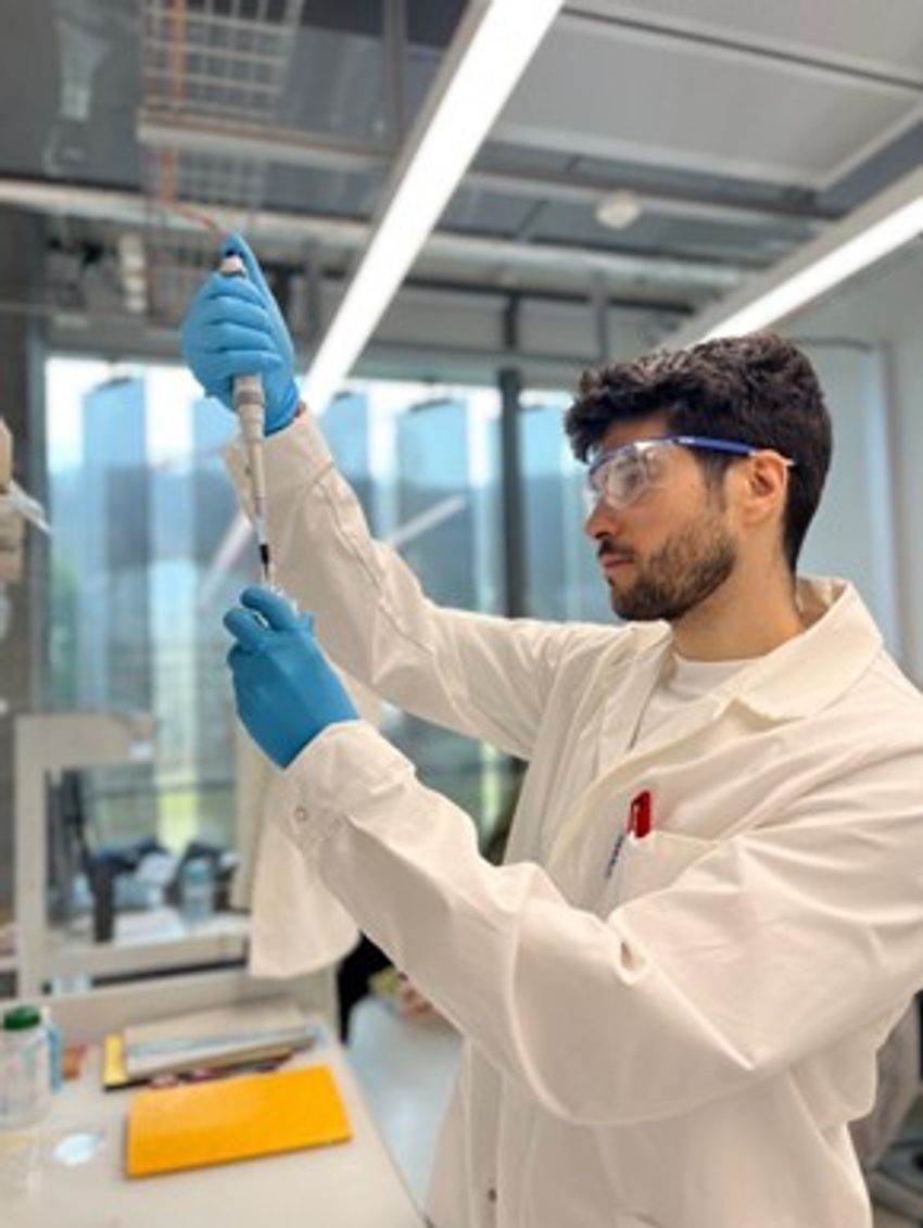 Lucas Dosnon wears protective glasses and a whitecoat and pipettes liquid in a lab.
