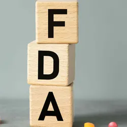 Block letters spell out FDA with pills on the ground next to them.