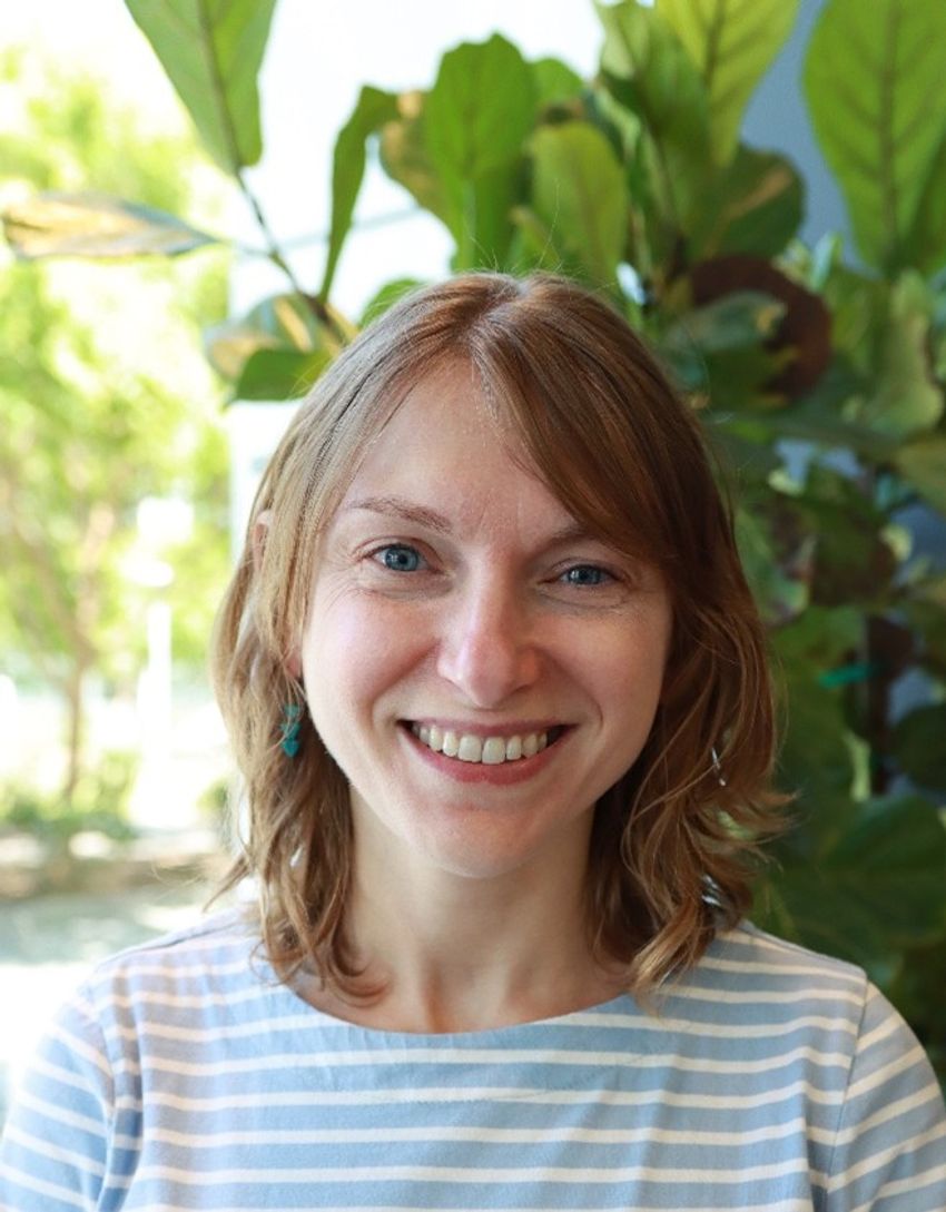 Yelena Bronevetsky smiling warmly in natural light with green foliage in the background. Yelena Bronevetsky smiling warmly in natural light with green foliage in the background.