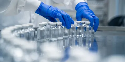 Gloved hands working in pharmaceutical factory manufacturing sterile bottles