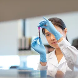 Scientist examining a blood sample in a lab for cancer biopsy testing.