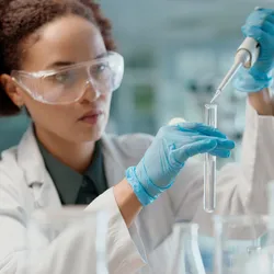 Scientist in lab using pipette for liquid testing in research on oral formulation technologies.