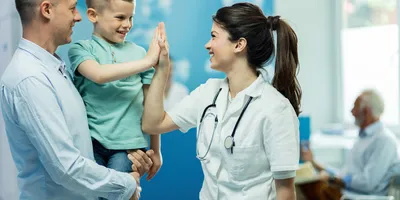 Medical person high-fiving a young boy in the hospital