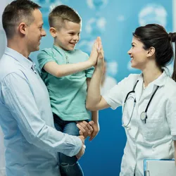 Medical person high-fiving a young boy in the hospital