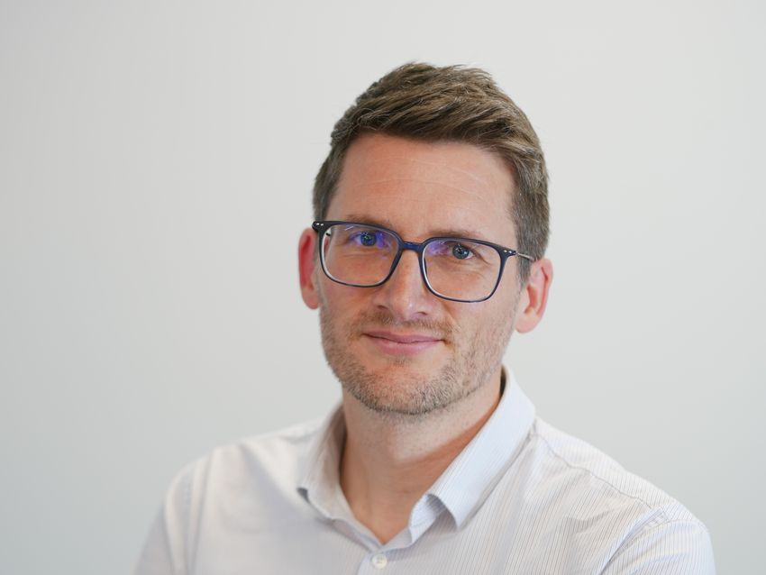 Robert Neely smiling in front of plain background