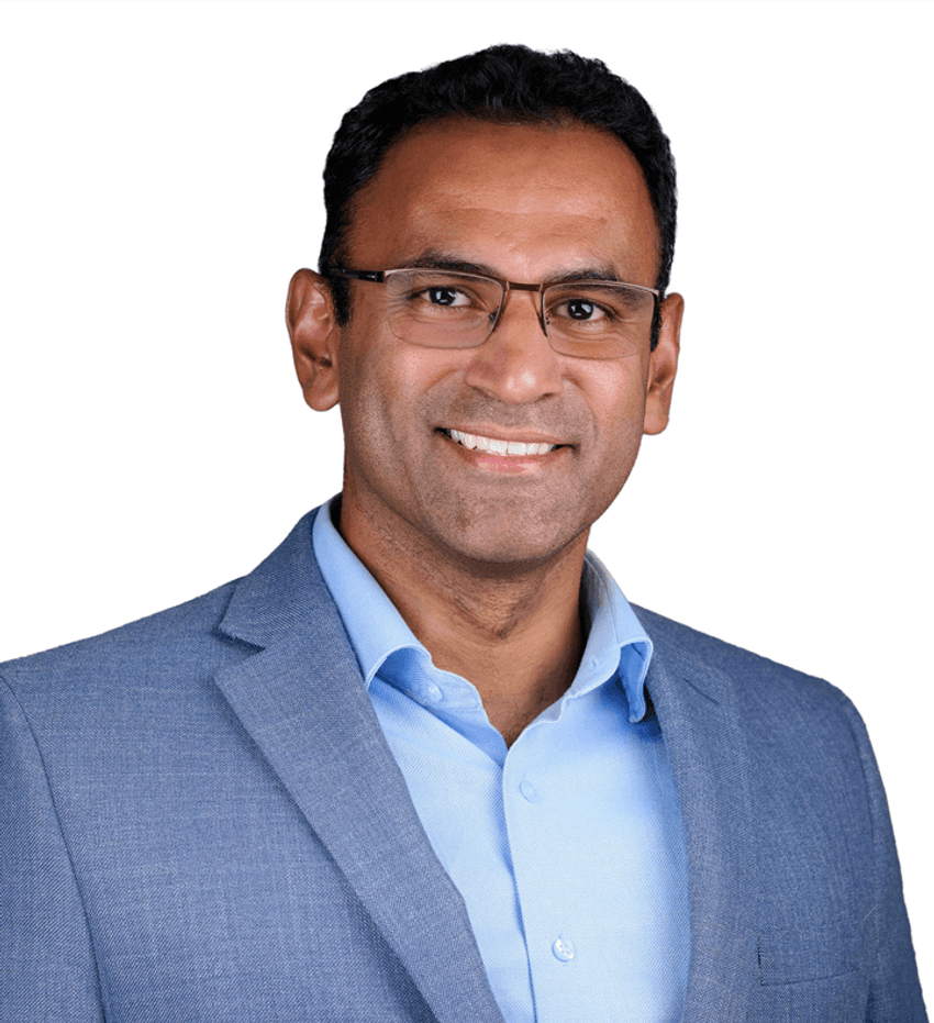 Emil Kuriakose in a suit and smiling in front of white background