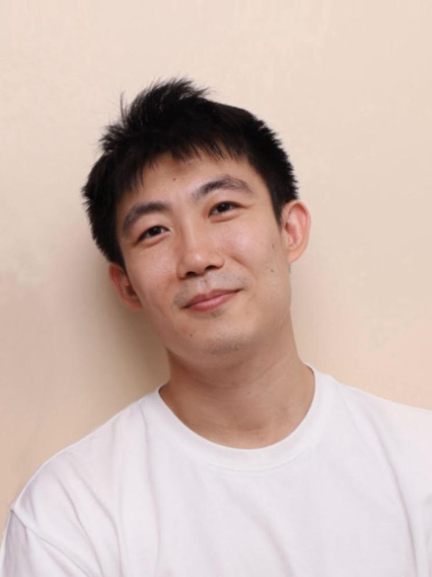 Boyang Wang smiling in a plain shirt in front of a plain background.