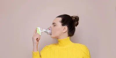 A lady using an inhaler to diagnose cancer. 