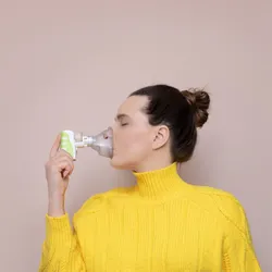 A lady using an inhaler to diagnose cancer. 