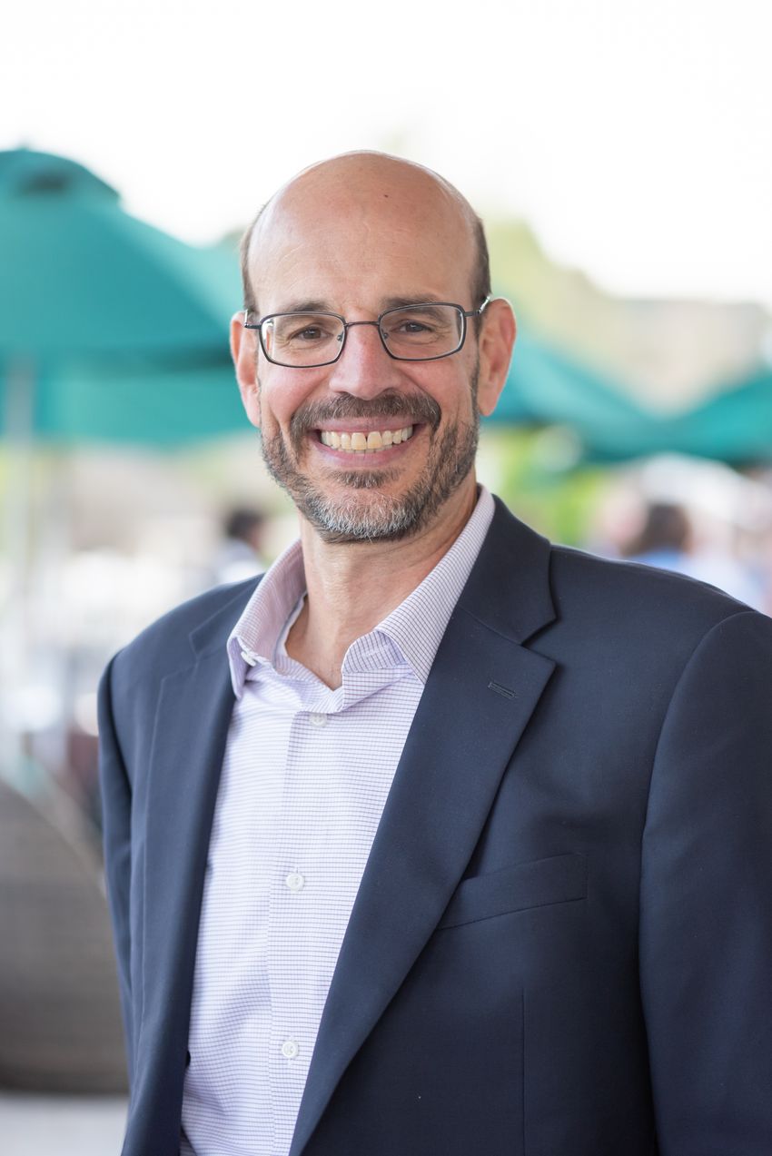 A portrait of a man wearing glasses in a suit. A portrait of a man wearing glasses in a suit.