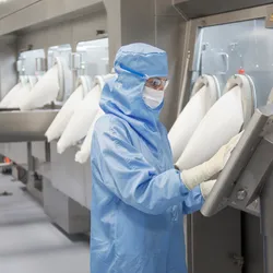 A person in protective clothing in a biologics lab