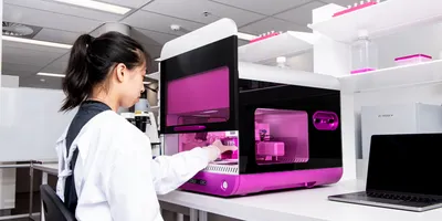 A scientist in lab PPE using the RASTRUM™ Allegro platform