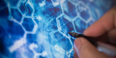 Close-up of a researcher using a stylus to draw or interact with digital molecular structures on a blue scientific interface.