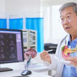 Older doctor explaining pancreatic cancer using ultrasound pictures and a 3D model to the patient. 