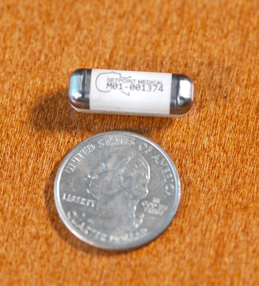Image of vitamin-sized SetPoint implant next to a US nickel for size comparison