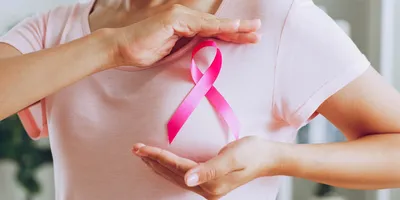 Woman shows pink ribbon as sign of Breast Cancer Awareness.