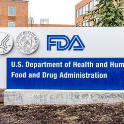 A photo of the white and blue FDA sign in front of an orange brick building.