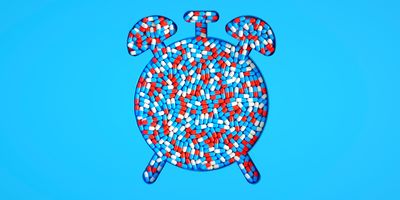 An alarm clock shape filled with red, white, and blue medicine capsules, symbolizing timely healthcare and medical treatment.