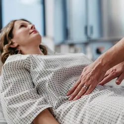 Doctor palpating woman's abdomen, using hands and steady pressure.