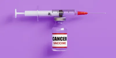 A syringe positioned horizontally above a small vial labeled “cancer vaccine” against a solid purple background.