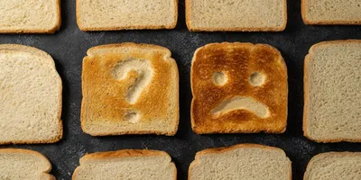 Slices of toasted bread with sad face and question sign.