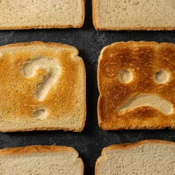 Slices of toasted bread with sad face and question sign.