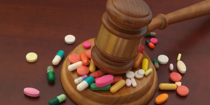 Wooden judge gavel with drugs on brown table