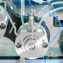 Binary pumps from an HPLC system are shown as three silver discs with blue and clear tubing against a clean laboratory background.