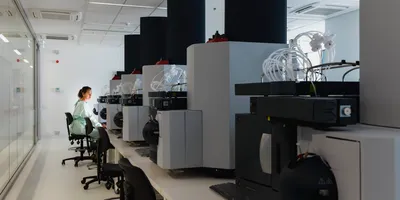 A female scientist sits amid large machinery in a leading medical research center.