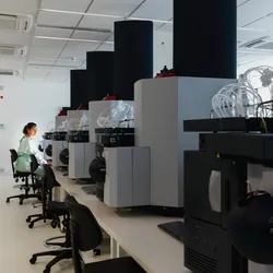 A female scientist sits amid large machinery in a leading medical research center. 