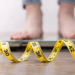 Feet on the scales, with a close-up of measuring tape.
