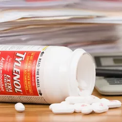 A spilled bottle of Tylenol pills and a pile of paperwork. 