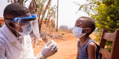A doctor holding a swab to perform a molecular test on a child in Africa.