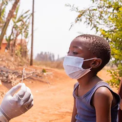 A doctor holding a swab to perform a molecular test on a child in Africa.