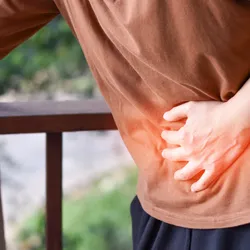Person clutching abdomen with hand, indicating pain. 