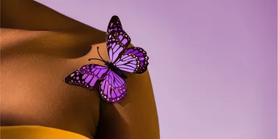 Cropped view of African American woman with purple butterfly on shoulder.