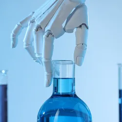 A robot hand reaches for a scientific flask. 