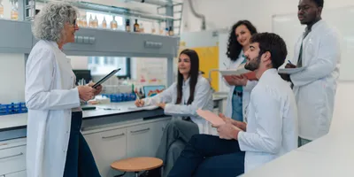 Diverse group of young adult students listening to their mature adult professor during a chemistry lecture in a lab