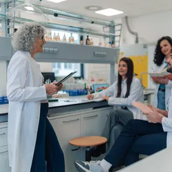 Diverse group of young adult students listening to their mature adult professor during a chemistry lecture in a lab